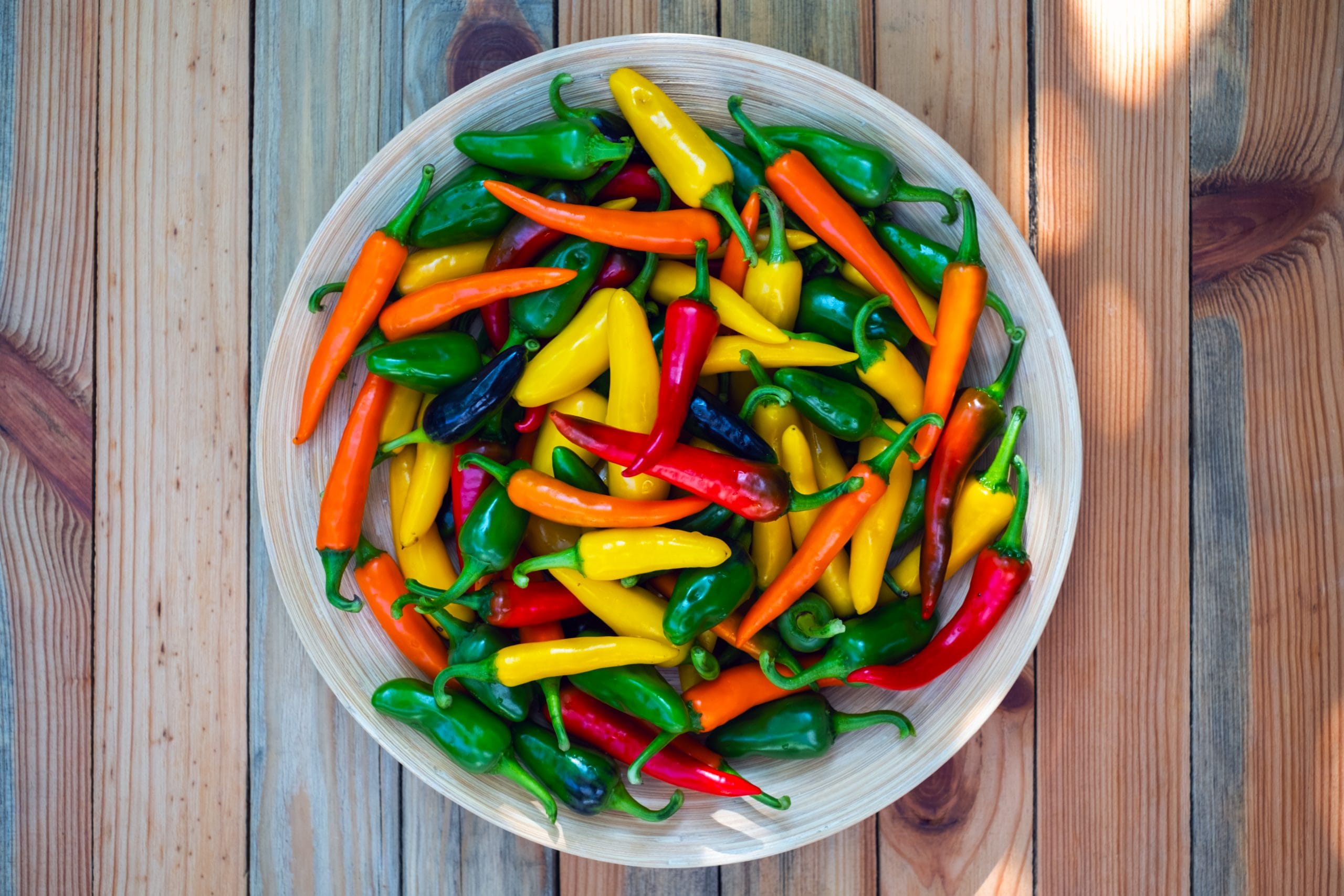 mixed colours hot peppers on wooden plate AE5VQ2K scaled