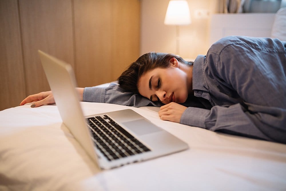 tired girl in pajama sleeping near laptop Y2DND9U