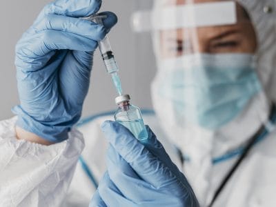 doctor holding preparing vaccine while wearing protective equipment