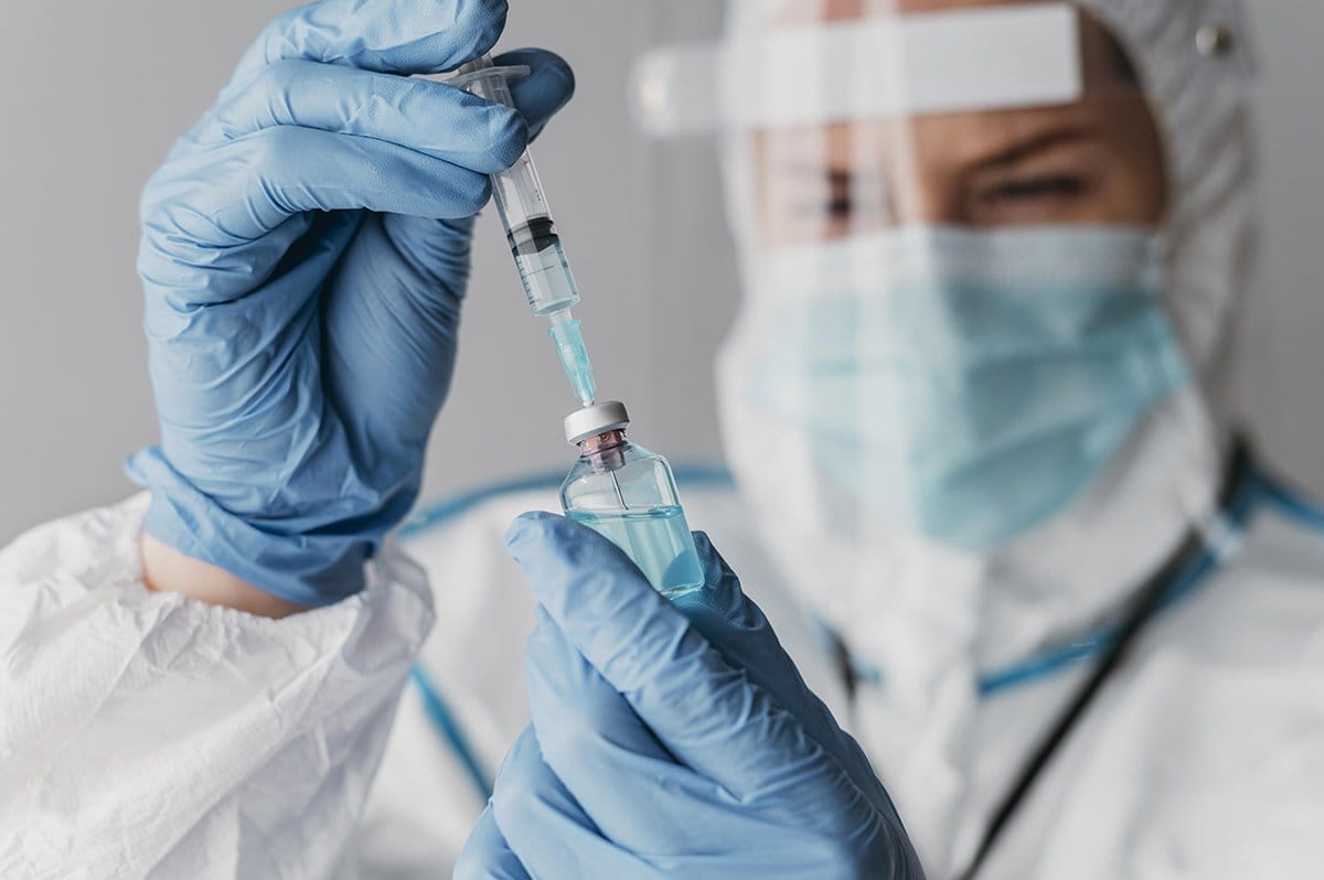 doctor holding preparing vaccine while wearing protective equipment